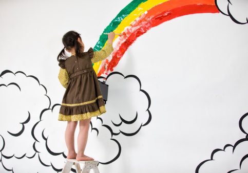 Girl draw rainbow on the wall