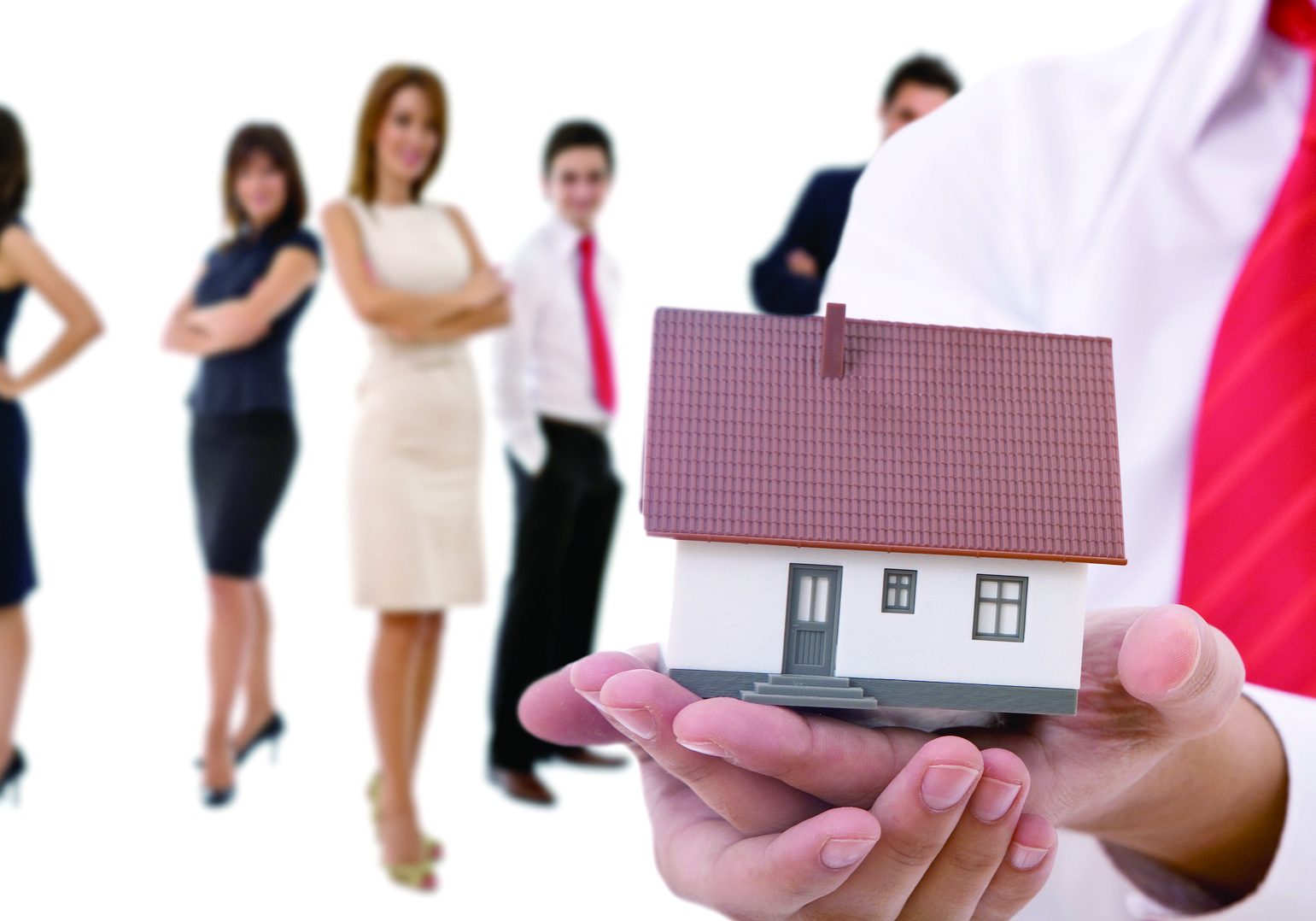 Businesspeople shaking hands and posing with dummy of house Businesspeople shaking hands and posing with dummy of house